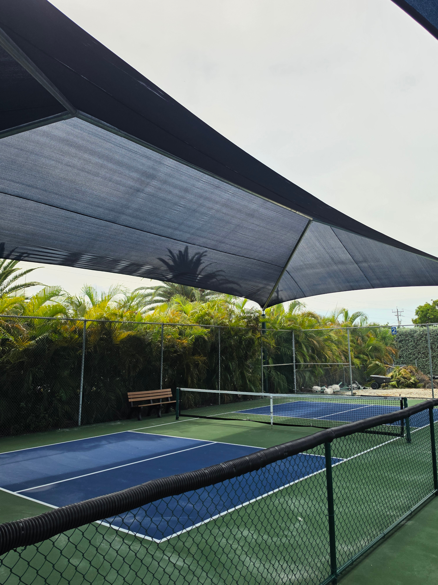 Shaded pickleball court at Key Colony Beach with palm trees and blue playing surface
