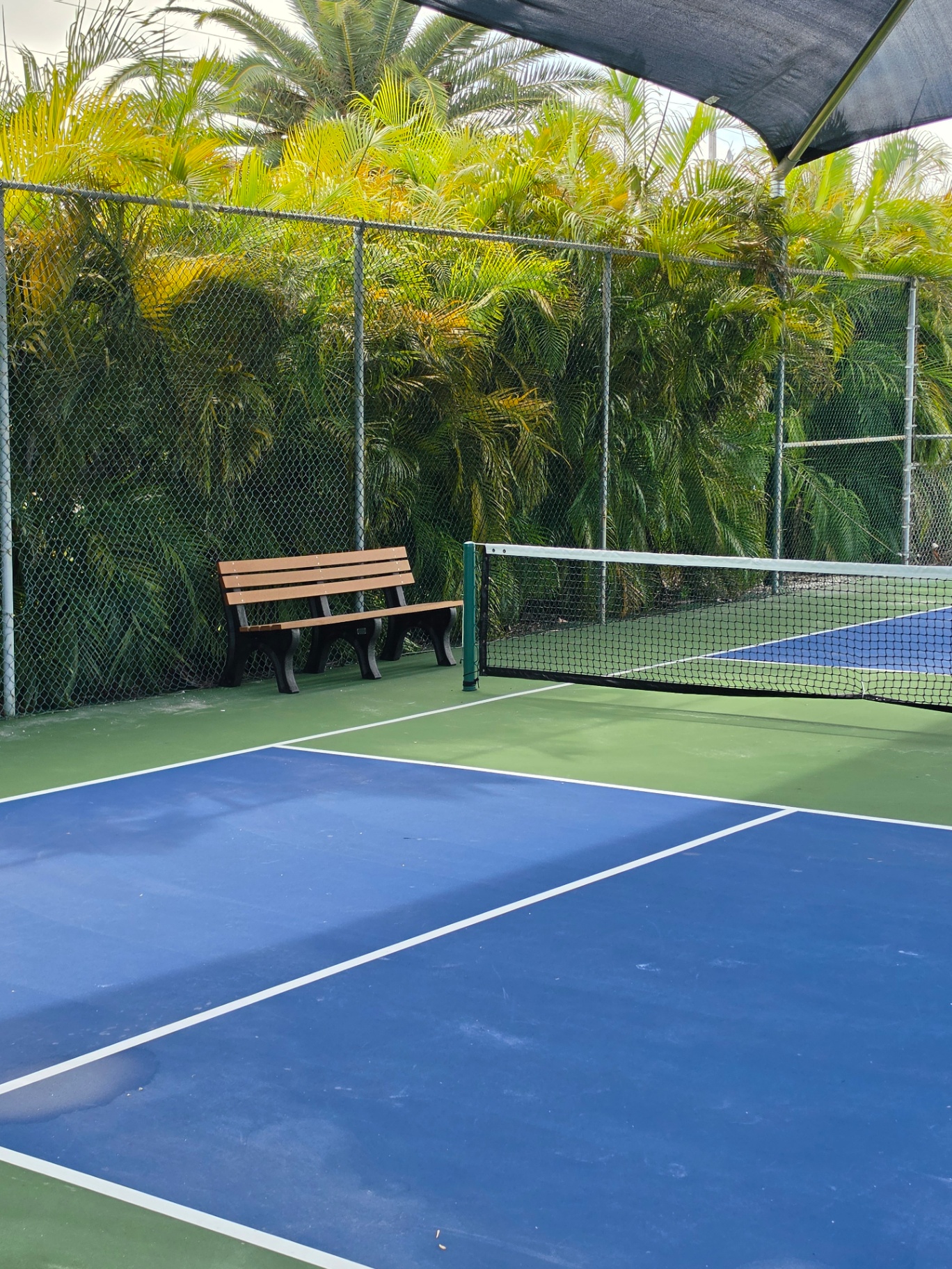 Freshly painted blue and green pickleball court under a shade sail at Key Colony Beach